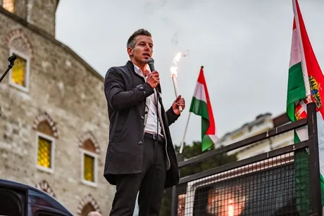 Péter Magyar vorbește la un miting, cu steaguri ungurești în fundal.