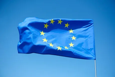 Steagul Uniunii Europene fluturând pe un fundal albastru senin.