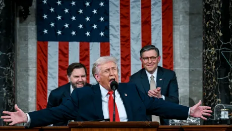 Donald Trump susține un discurs în fața Congresului, cu steagul american în fundal.