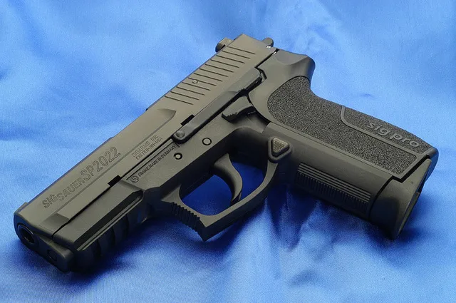 Pistol SIG Sauer pe un fundal albastru, simbol al industriei de apărare.