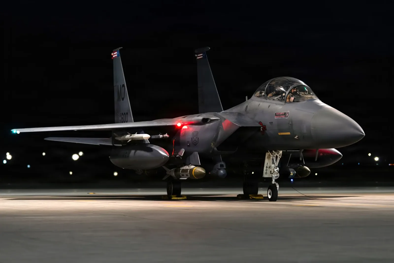 Avion militar pregătit pentru misiune în întuneric, cu lumini aprinse.