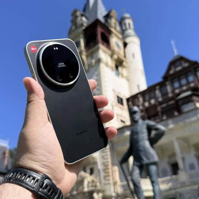 Un telefon Leica Leitzphone în fața unui castel, cu cer albastru în fundal.