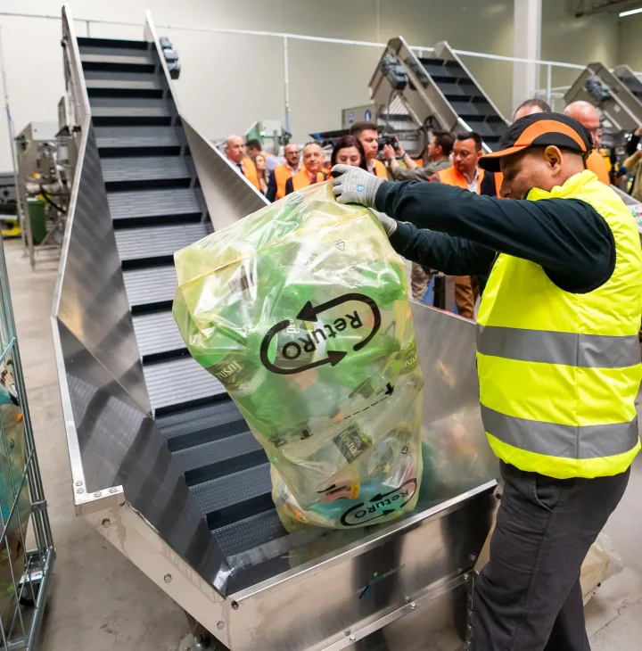 Un angajat sortează ambalaje pe o bandă de reciclare.