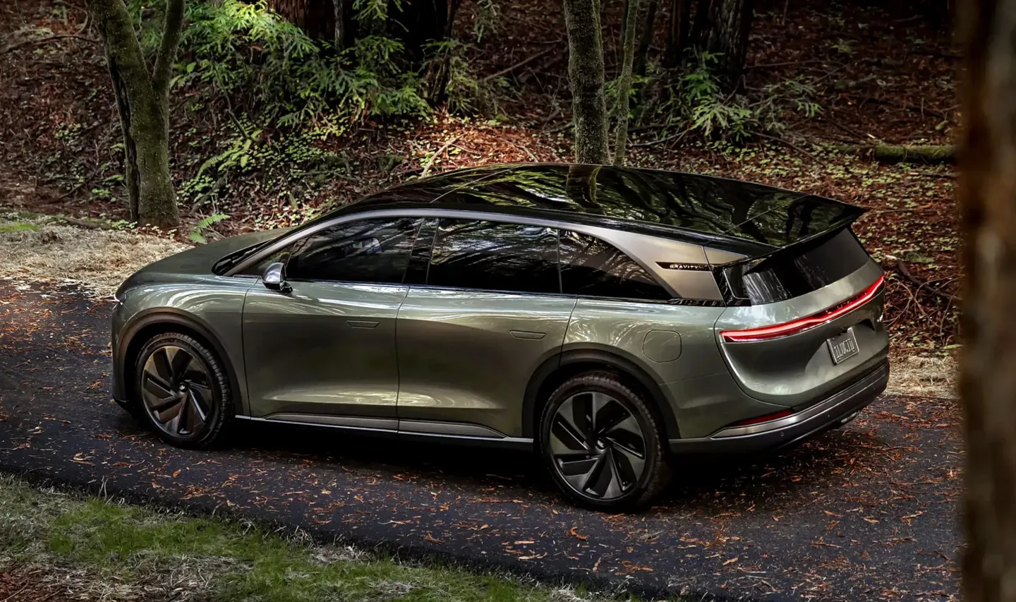 Un SUV electric Lucid parcurs pe un drum înconjurat de natură.