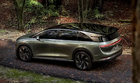 Un SUV electric Lucid parcurs pe un drum înconjurat de natură.