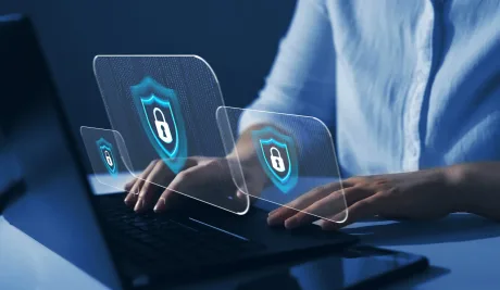 O persoană lucrează la un laptop cu simboluri de securitate.