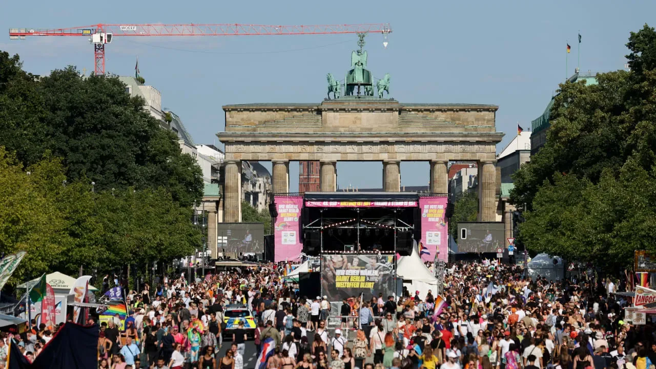 Mulțime adunată la un eveniment festiv în Berlin, cu monumente istorice în fundal.