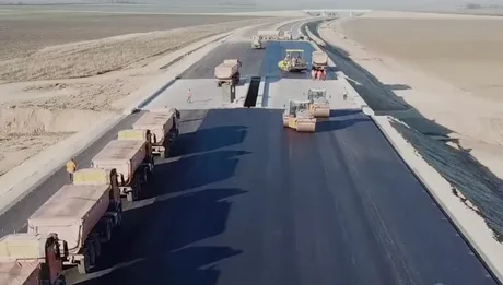 Lucrări pe autostrada A7, cu utilaje și camioane pe șantier.