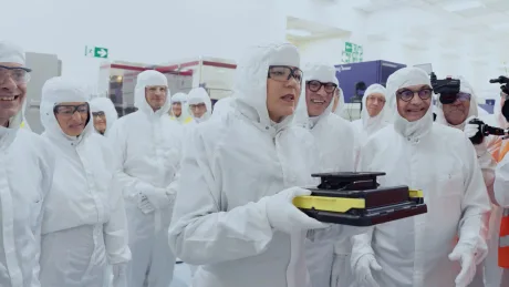 Grup de oameni în costume de protecție, inspectând cipuri.