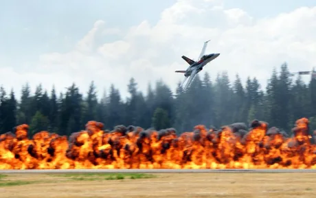 Avion de luptă în zbor deasupra unei explozii spectaculoase.