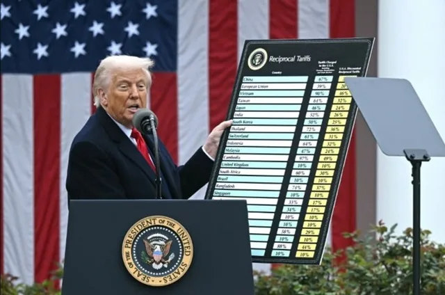 Donald Trump anunțând măsuri comerciale în fața steagului american.