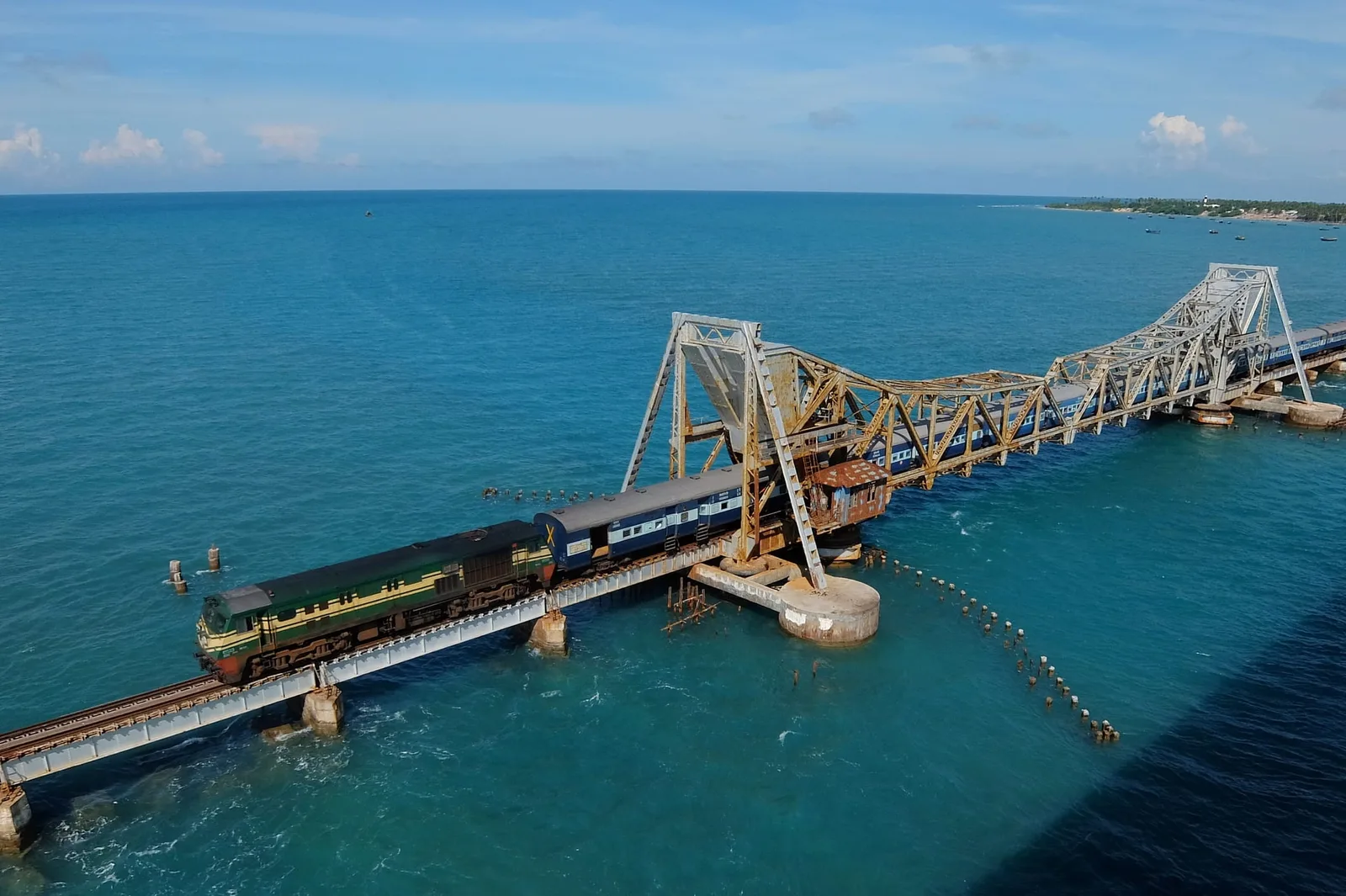 Tren traversând un pod feroviar pe apă, în peisajul oceanic.