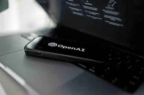 Dispozitive tehnologice cu logo OpenAI pe un laptop deschis.