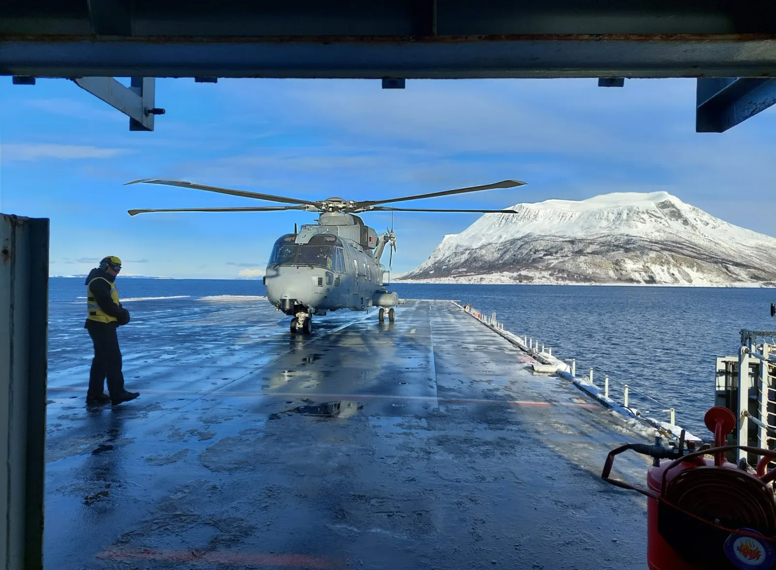 Un elicopter pe o platformă, pe fundal munți acoperiți de zăpadă.