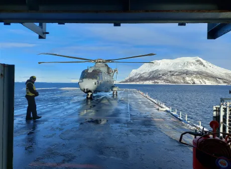 Un elicopter pe o platformă, pe fundal munți acoperiți de zăpadă.