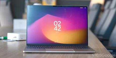 Laptop cu ecran colorat, afișând ora și un design modern.
