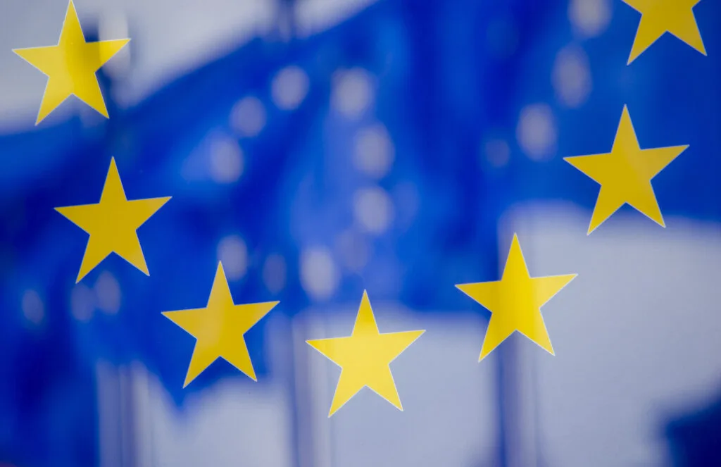 Steaguri ale Uniunii Europene fluturând în vânt, simbolizând extinderea și cooperarea.