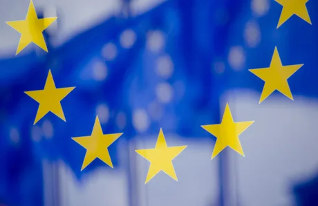 Steaguri ale Uniunii Europene fluturând în vânt, simbolizând extinderea și cooperarea.