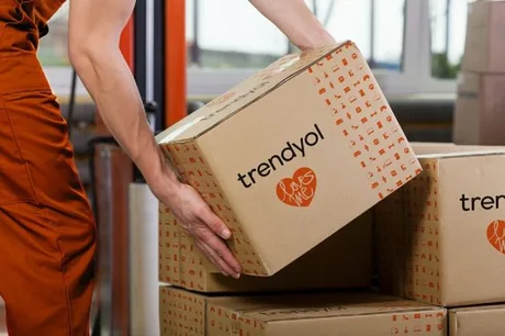 Un angajat manipulează cutii cu logo-ul Trendyol într-un depozit.