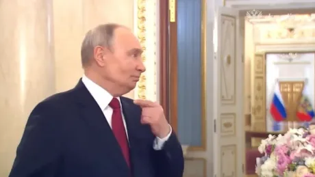Vladimir Putin discutând la Kremlin, cu decor elegant în fundal.