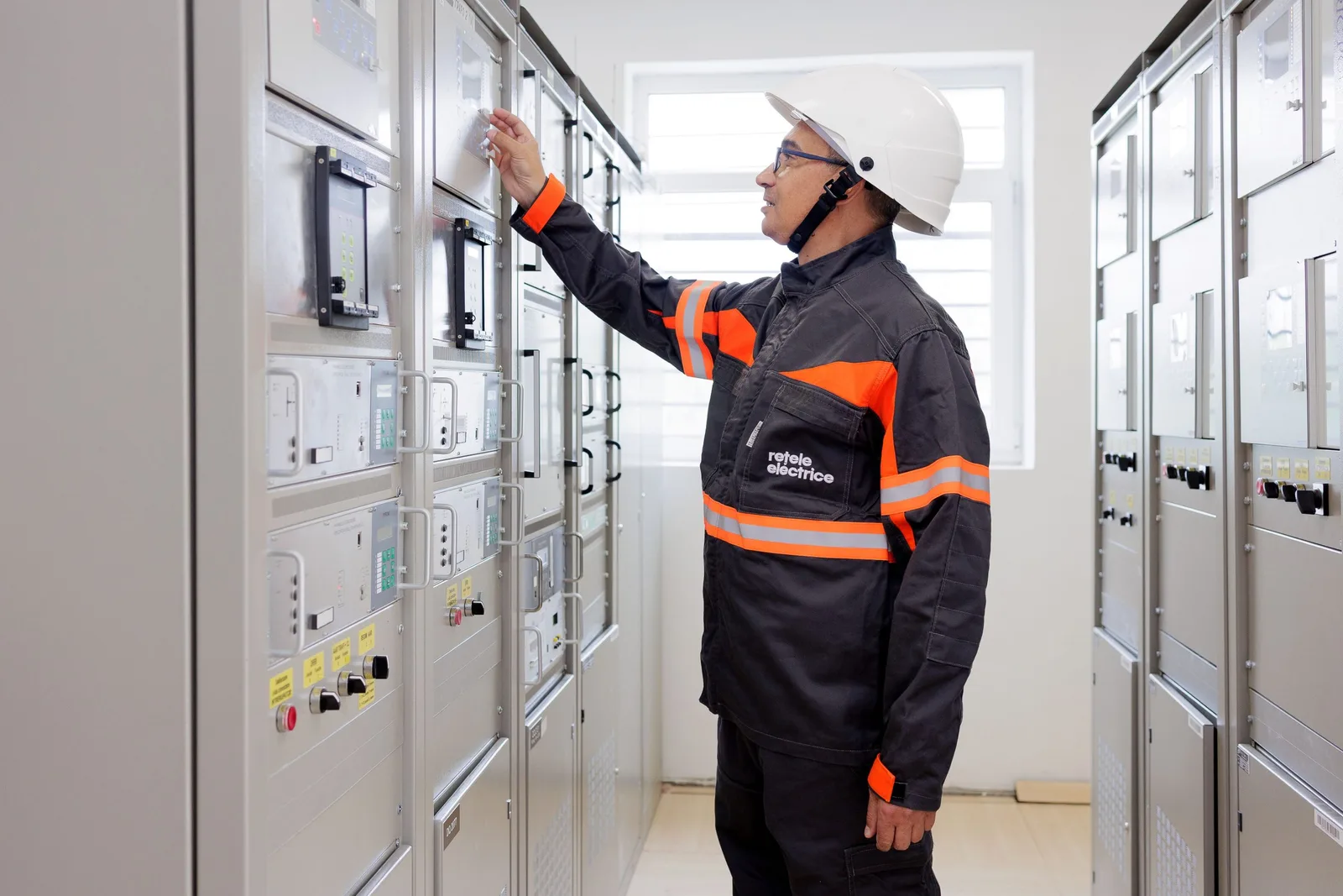 Tehnician verificând echipamente electrice într-o stație de distribuție modernizată.