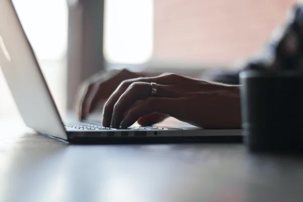 Mâini care tastează pe un laptop, simbolizând digitalizarea.