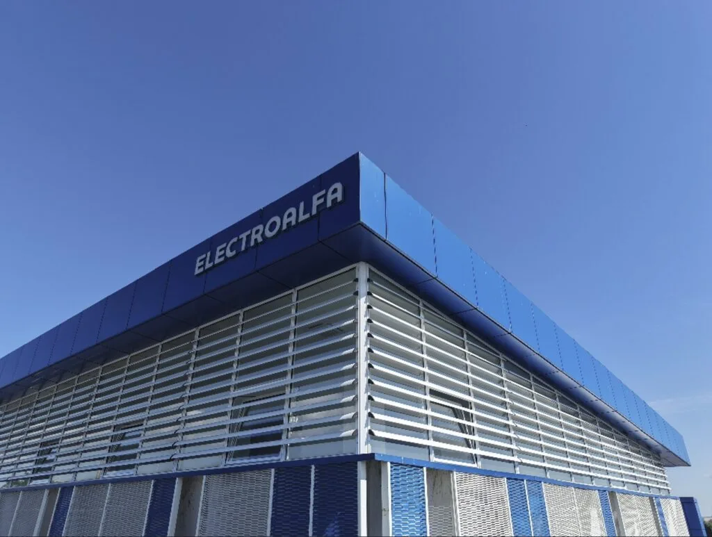 Sediul Electro-Alfa International sub un cer senin, simbolizând finalizarea achiziției.