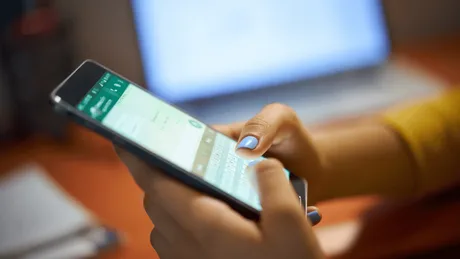 Utilizator care explorează aplicația WhatsApp pe un telefon mobil.