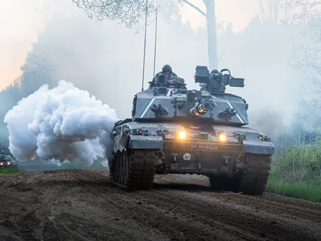 Tanc militar în acțiune, cu fum alb ieșind din țevile de evacuare.