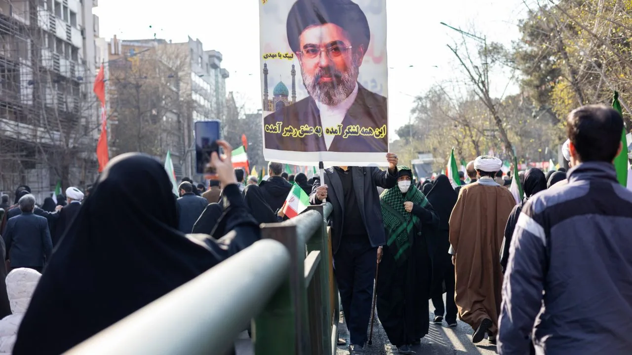 Protest în Iran cu oameni purtând pancarte și steaguri naționale.