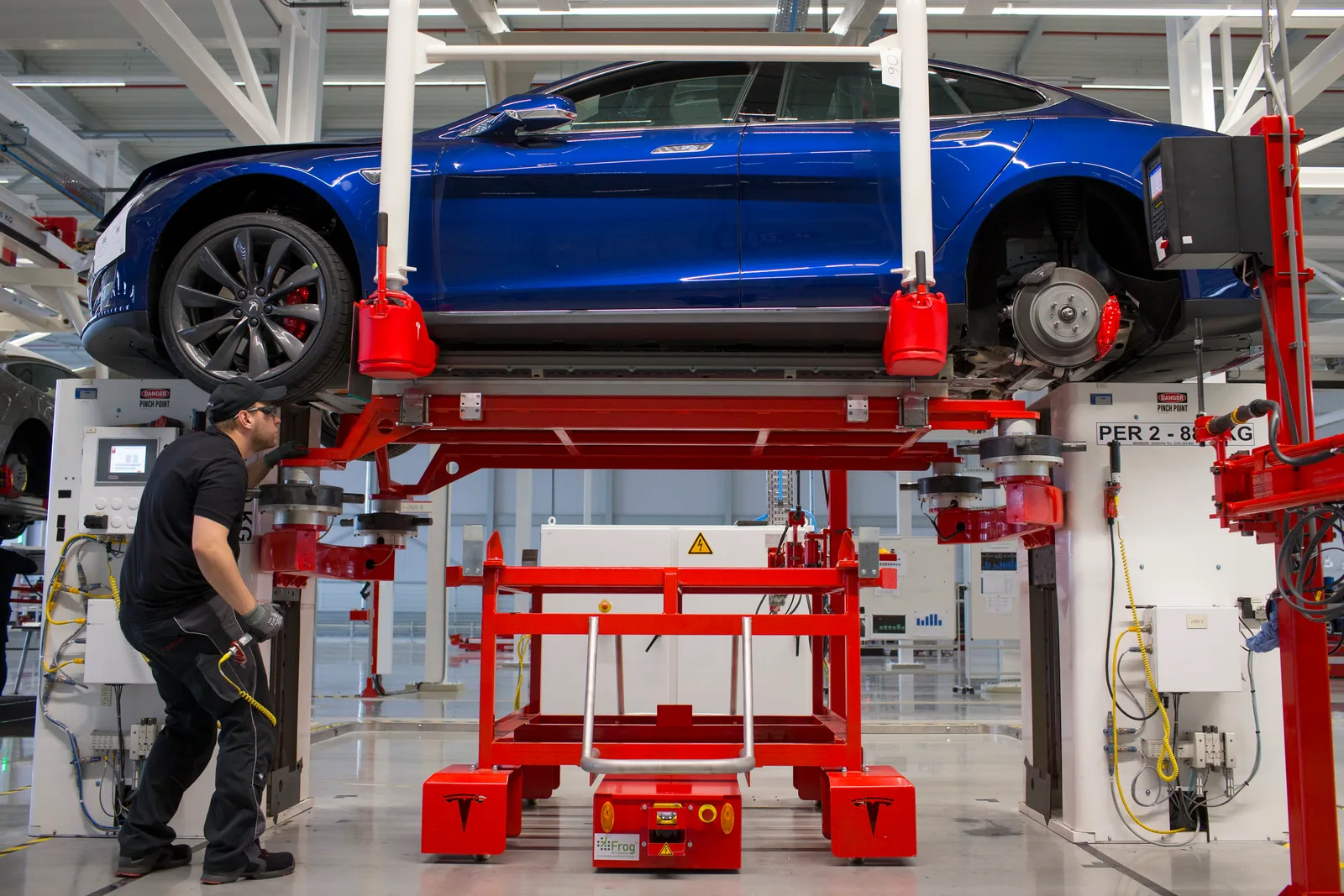 Un angajat lucrează la un vehicul electric Tesla în fabrică.