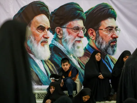 Oameni ascultând discursuri în fața unui mural cu lideri iranieni.