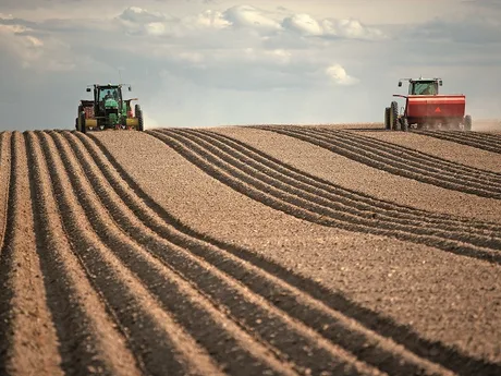 Tractoare lucrând pe un câmp pregătit pentru agricultură.