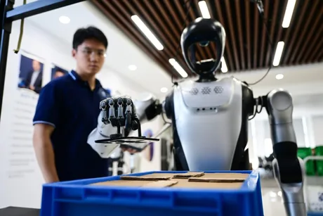 Un robot umanoid interacționează cu un om într-un mediu de lucru modern.
