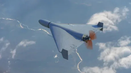 Dronă autonomă zburând deasupra unui peisaj cu nori și teren.
