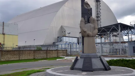 Monument dedicat dezastrului de la Cernobîl, cu centrala în fundal.