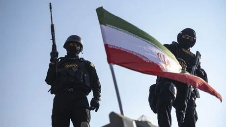 Doi soldați iranieni în fața steagului național, pregătiți pentru orice situație.