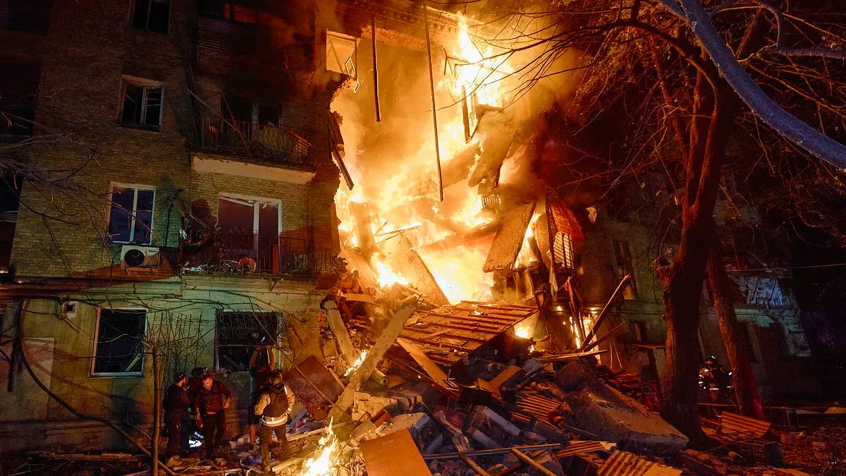 Clădire distrusă în urma unui atac cu rachete, flăcări și fum în jur.