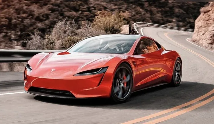 Un automobil Tesla Roadster roșu pe un drum montan, în mișcare rapidă.
