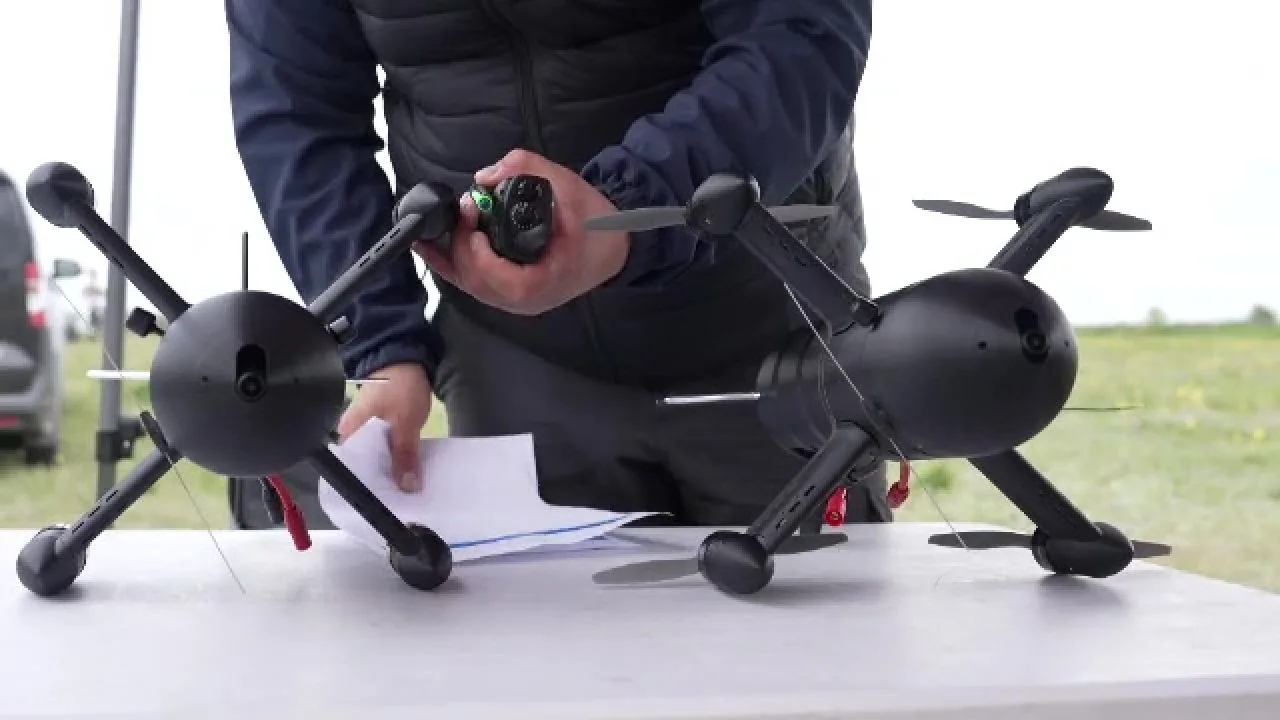 Un bărbat pregătește drone pentru utilizare pe un birou în aer liber.