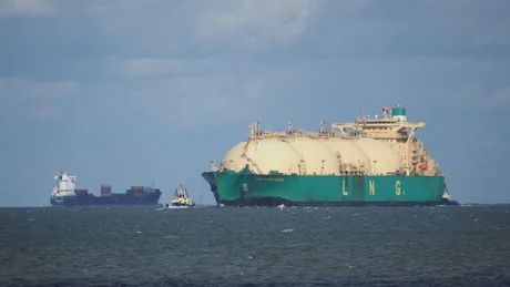 Nave de transport GNL navigând pe mare, cu cer senin în fundal.
