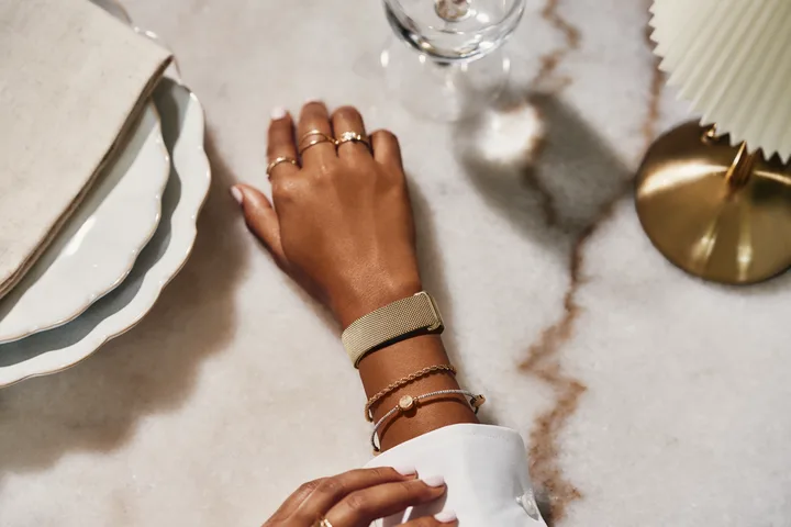 Brățară Fitbit Air pe o mână, pe un fundal elegant de masă.