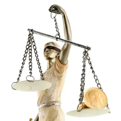 Statuie a Justiției cu balanța și monede, simbolizând echilibrul și corectitudinea.