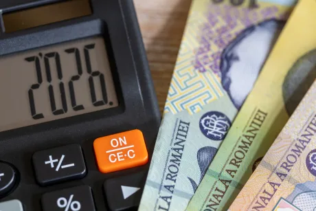 Bancnote românești și un calculator pe masă.
