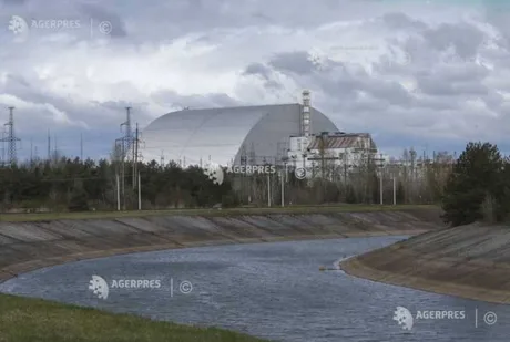 Peisaj cu centrala de la Cernobîl și apă în prim-plan.