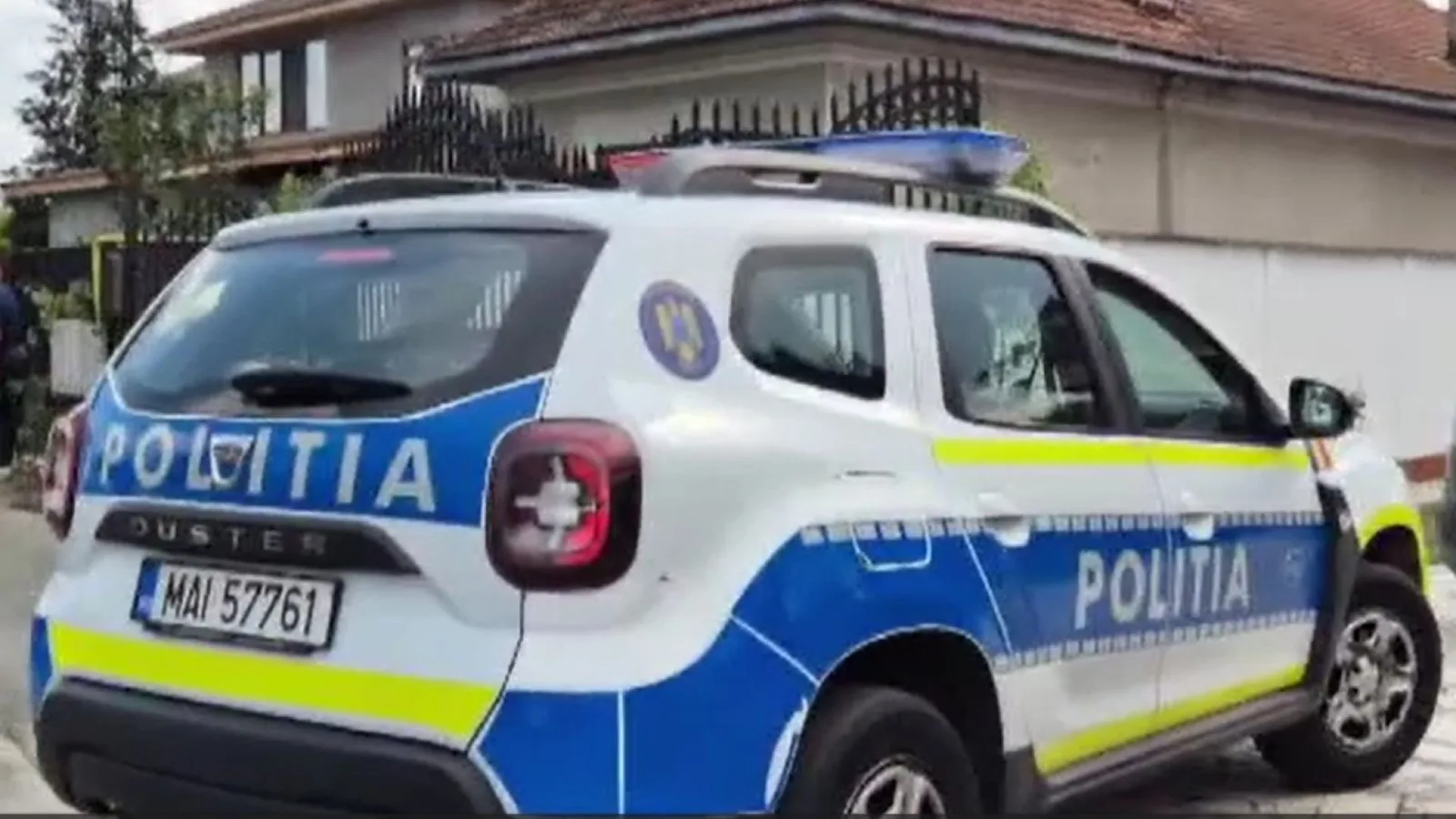 Mașină de poliție parcata în fața unei locuințe în timpul perchezițiilor.