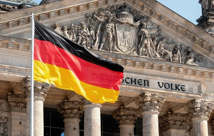 Steag german fluturând în fața unei clădiri istorice din Berlin.