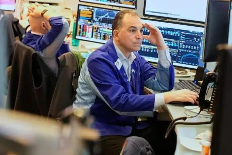 Trader concentrat la birou, monitorizând graficele bursiere.