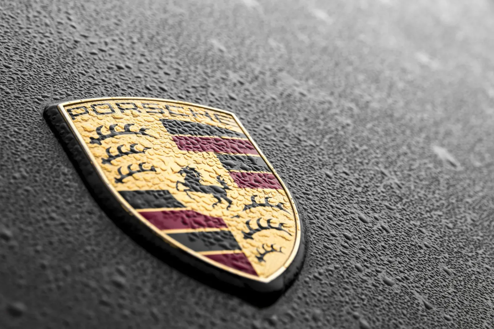 Sigla Porsche pe un fundal umed, simbol al brandului de lux.