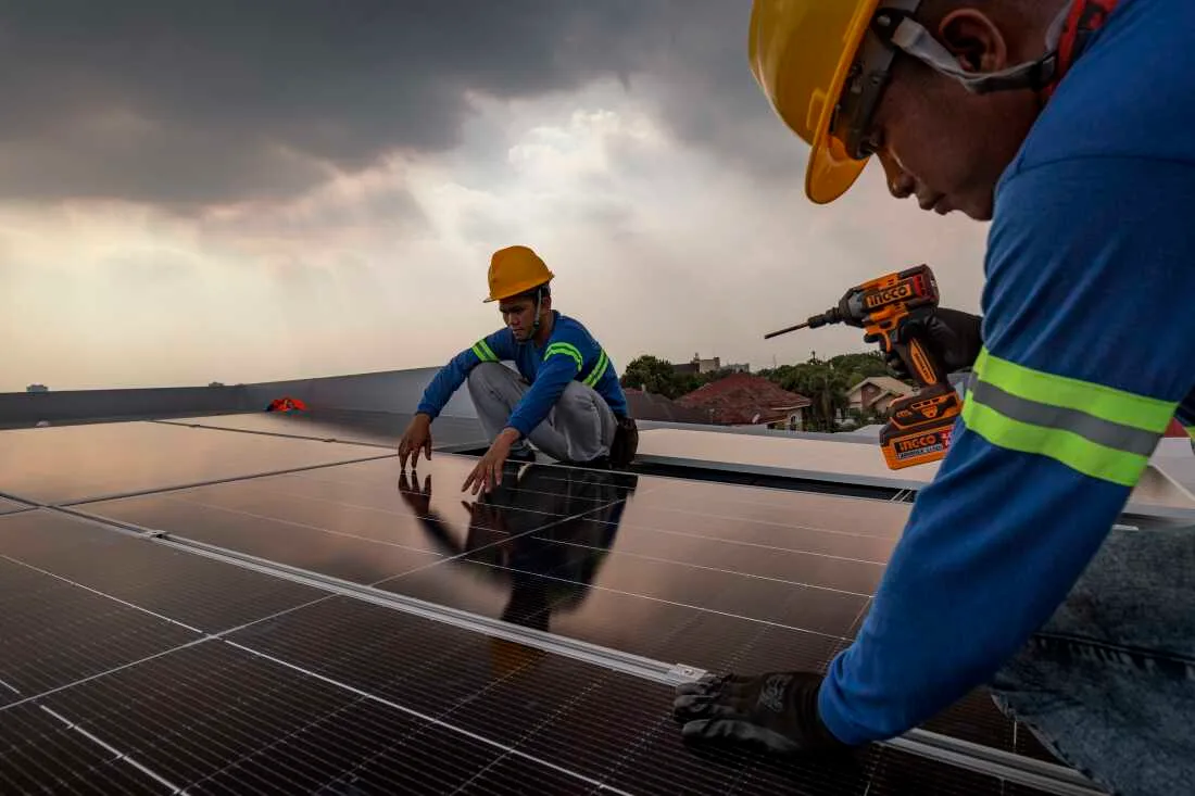 Instalare de panouri solare de către muncitori pe un acoperiș.
